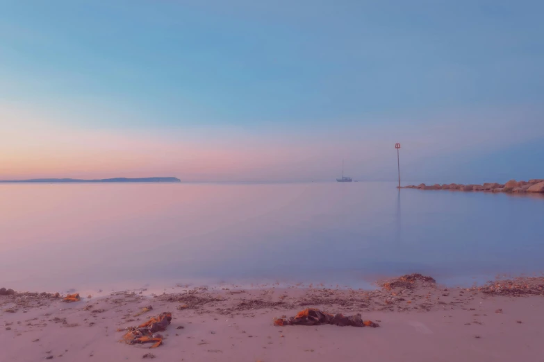 the sun is rising behind a lone boat near a calm bay