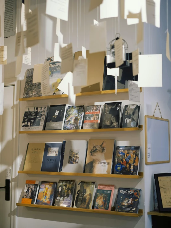 several books are hung above a window with papers hanging on it