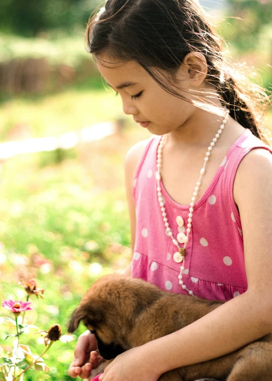 a girl holding a puppy while wearing a pearl necklace