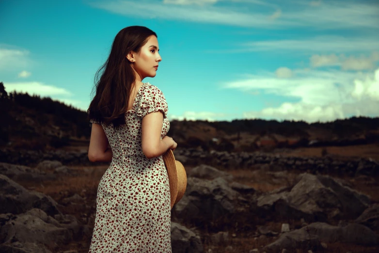 a young woman standing next to a rocky hillside