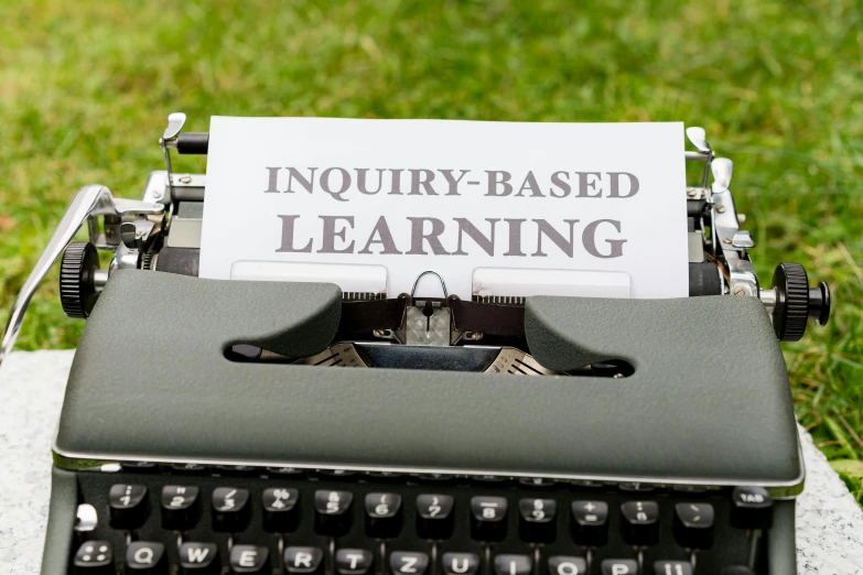 an antique typewriter with a card saying inquiring - based learning