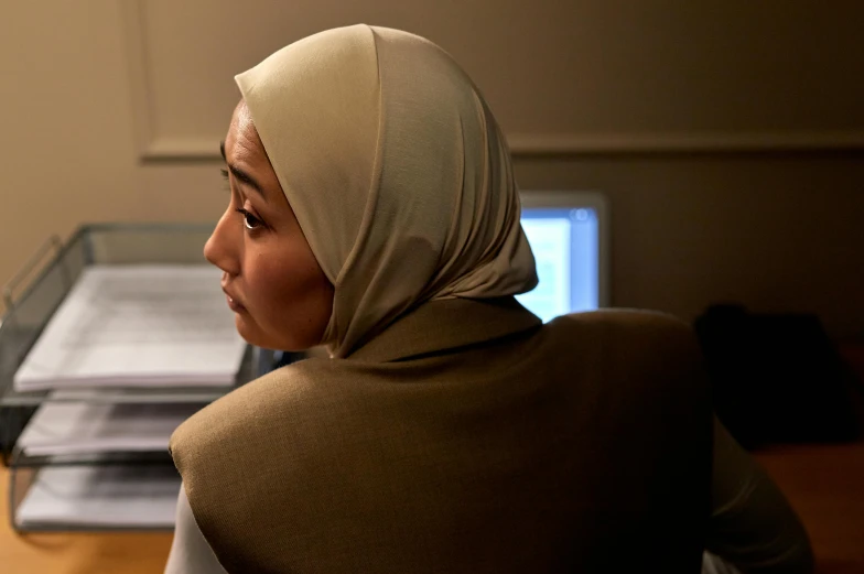 a young woman with a hijab standing in front of a printer