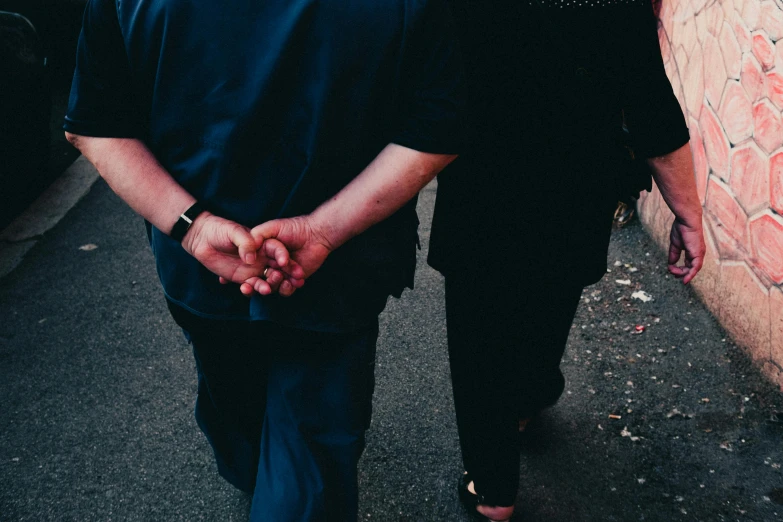 two people walking down the street holding hands