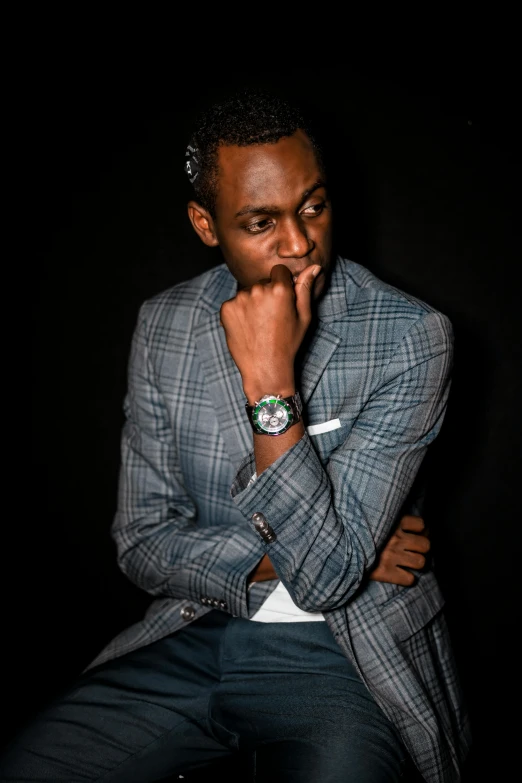 a black man sitting in front of a black background