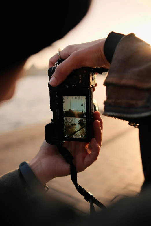 someone taking pictures with their mobile phone at sunset