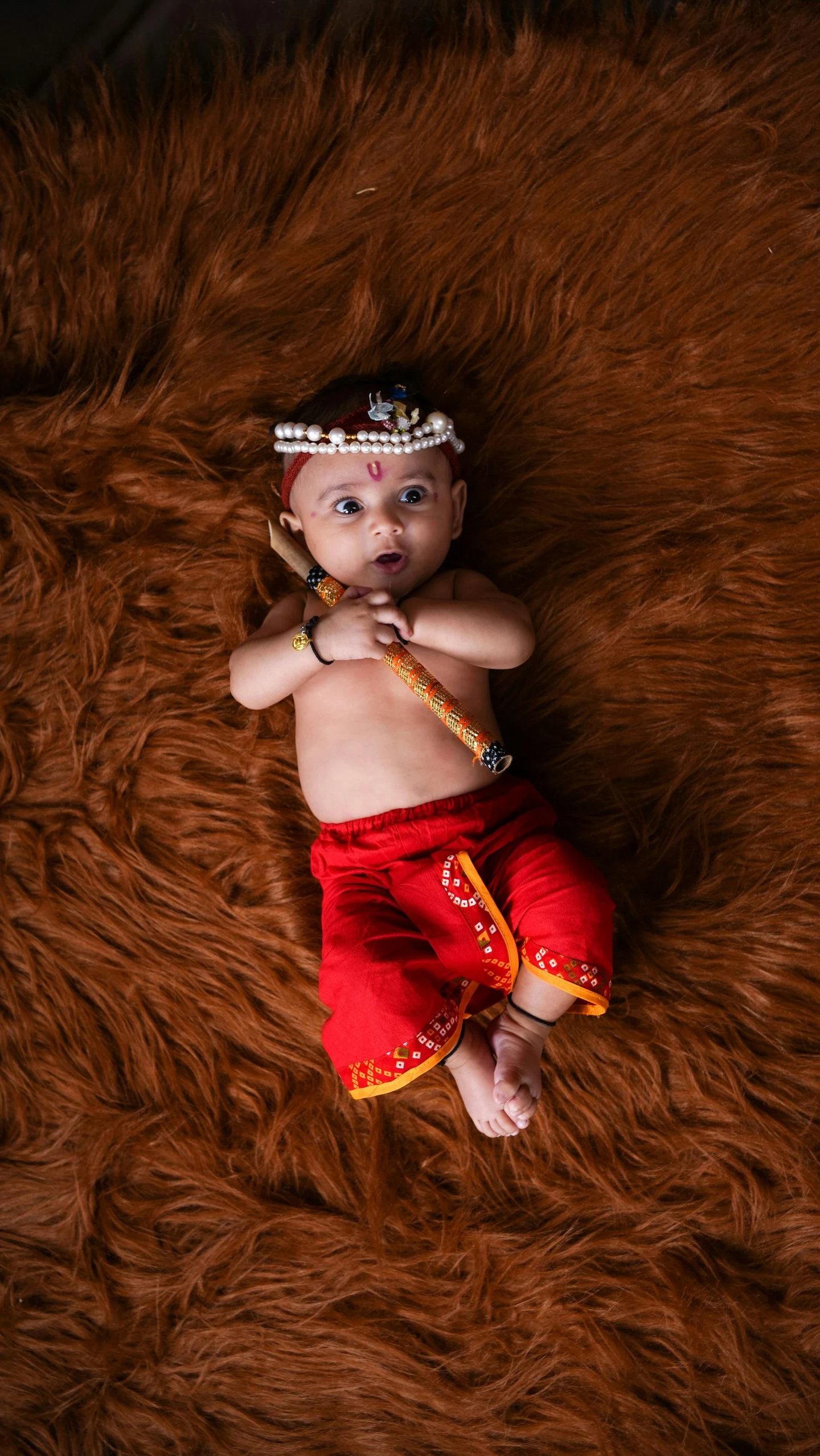 an adorable baby in a hula skirt on a furry surface