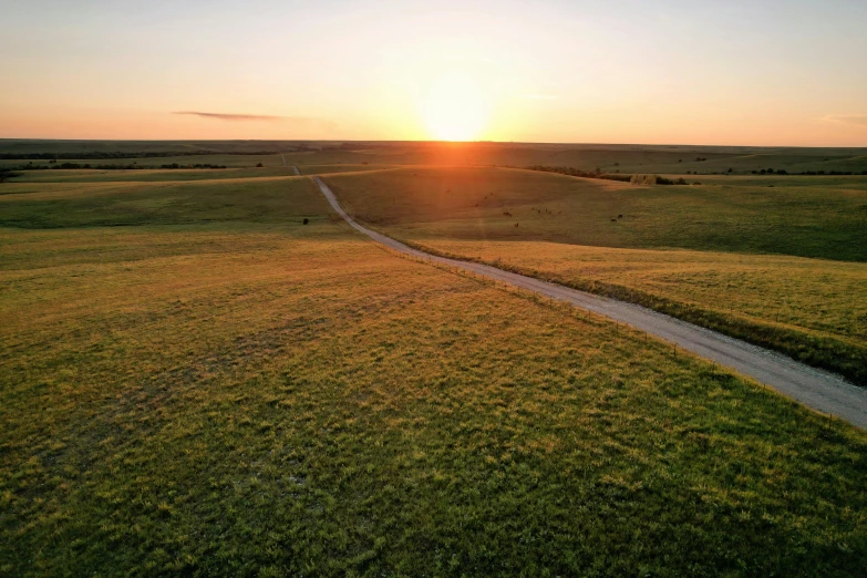 an aerial po of the sun rising above a field