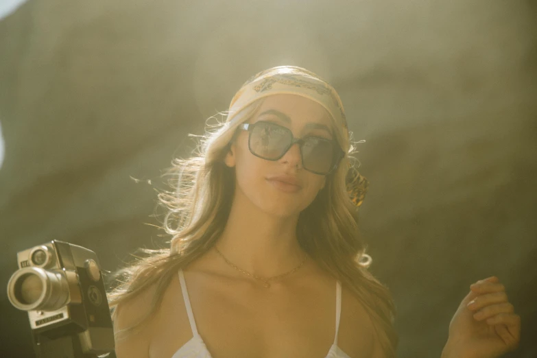 a woman wearing a white shirt with dark glasses and holding a gun