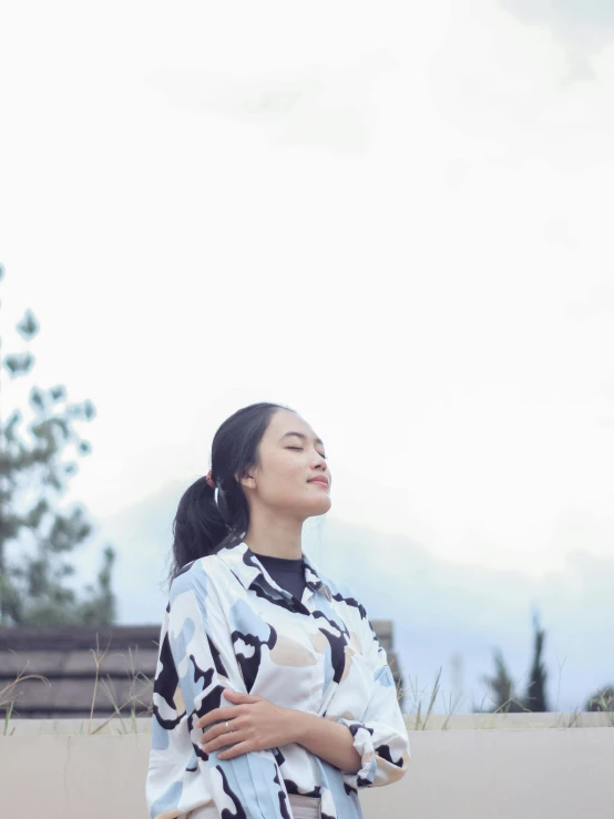 an asian woman standing on a wall with her arms folded