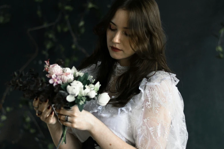 a woman holding a bunch of flowers near a plant