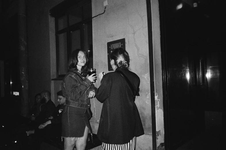 two people stand on the wall while looking at their phones