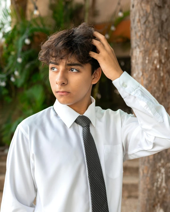 the young man is adjusting his tie while he looks to his left