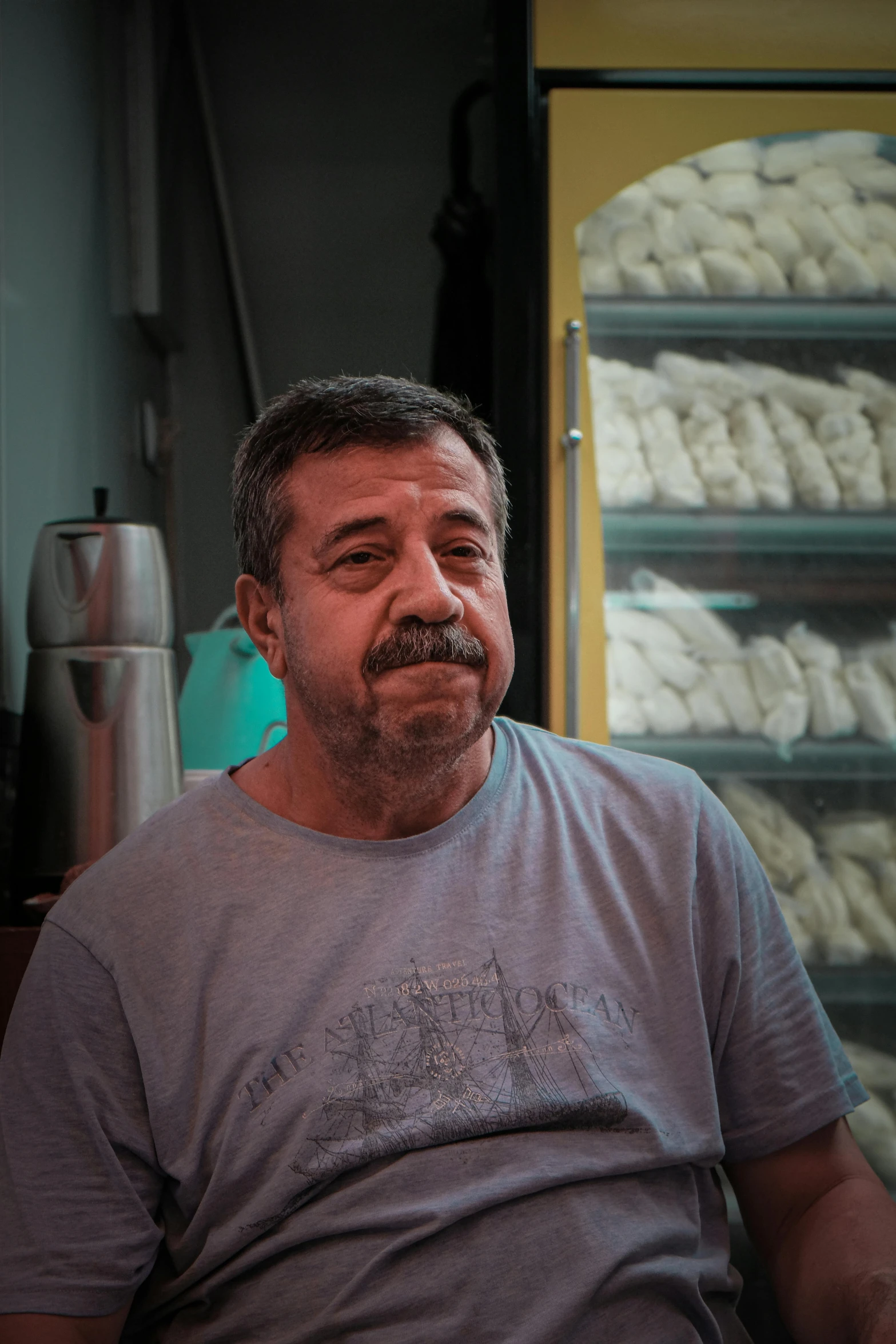 a bearded man sitting in front of a display case