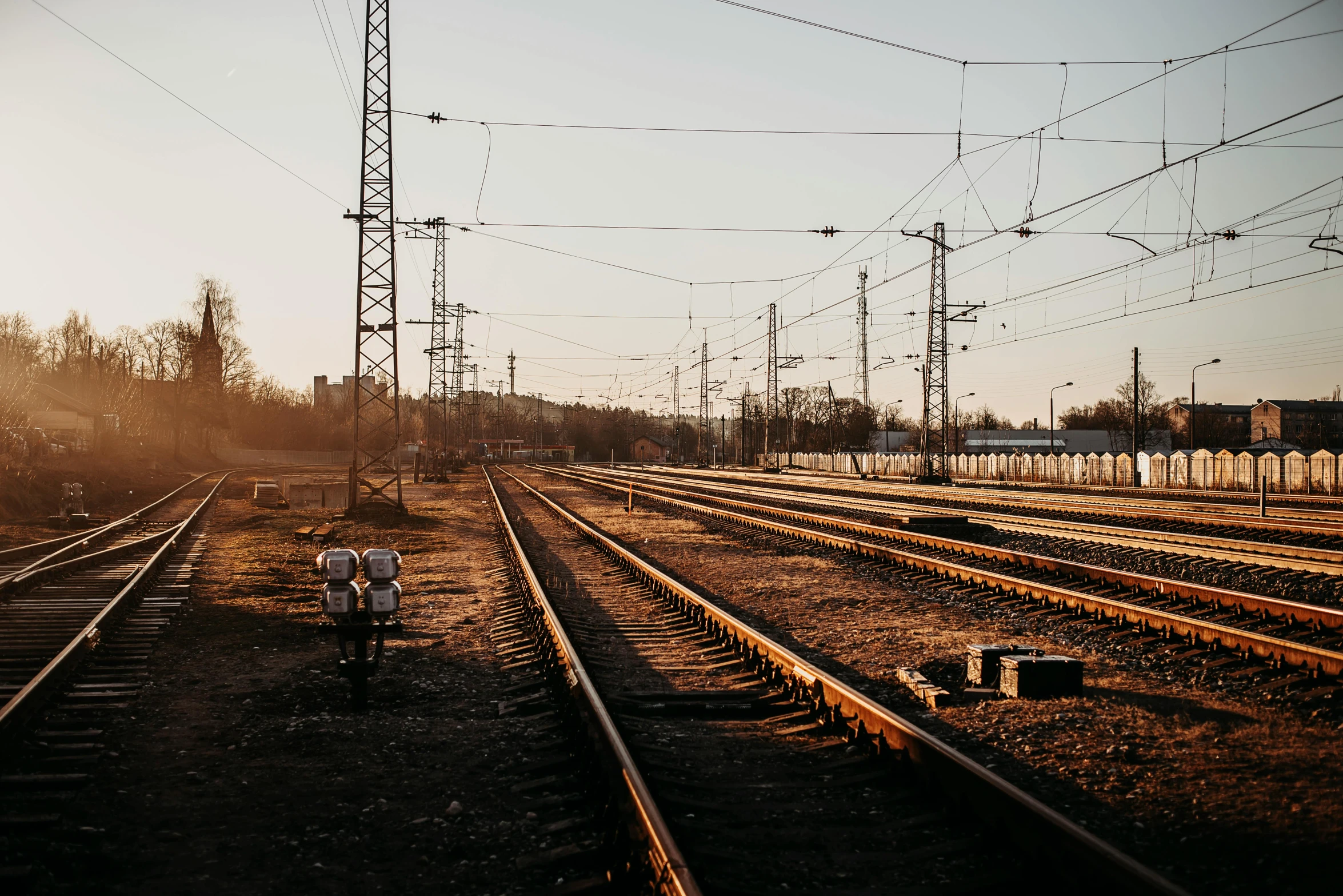 the sun sets behind some train tracks in the distance