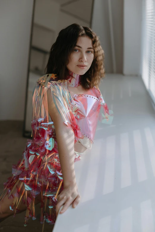 young woman in plastic dress leaning on edge of table