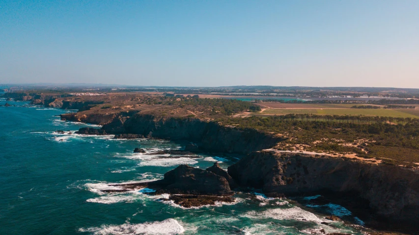 an ocean view of a rocky coastline surrounded by forested area