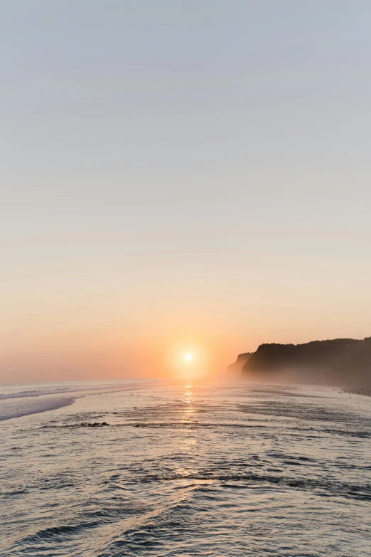 the sun is setting over the water at the beach