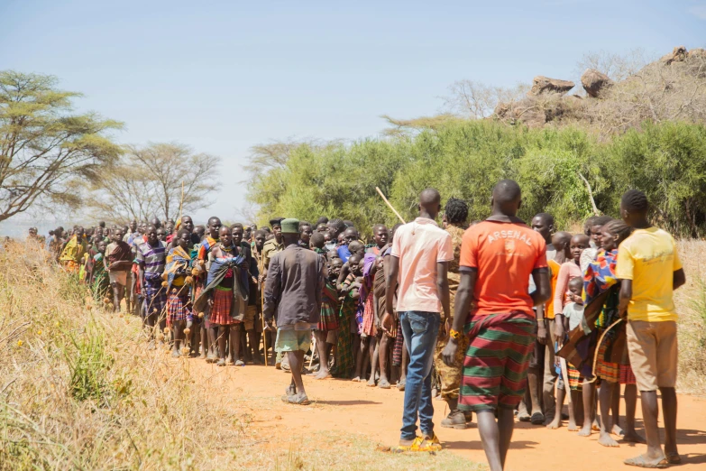 a large group of men standing on a dirt road