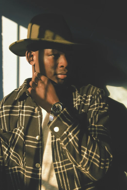 a young man wearing a hat while leaning against a wall