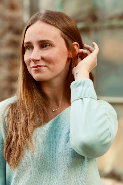 a lady that is wearing a blue sweater is holding some earrings