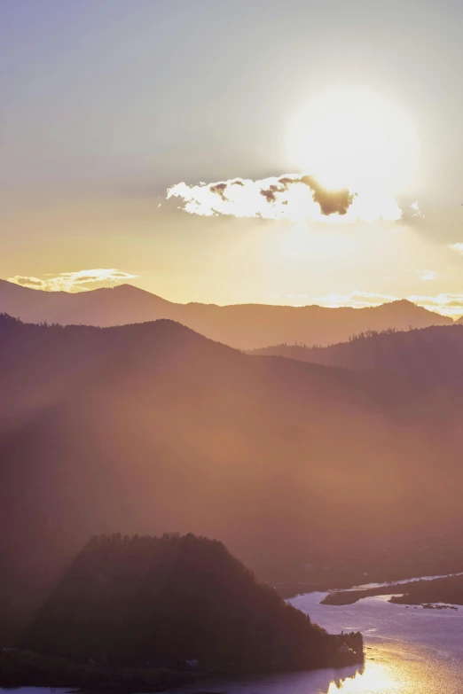 the sun rises behind the mountains in an area with water