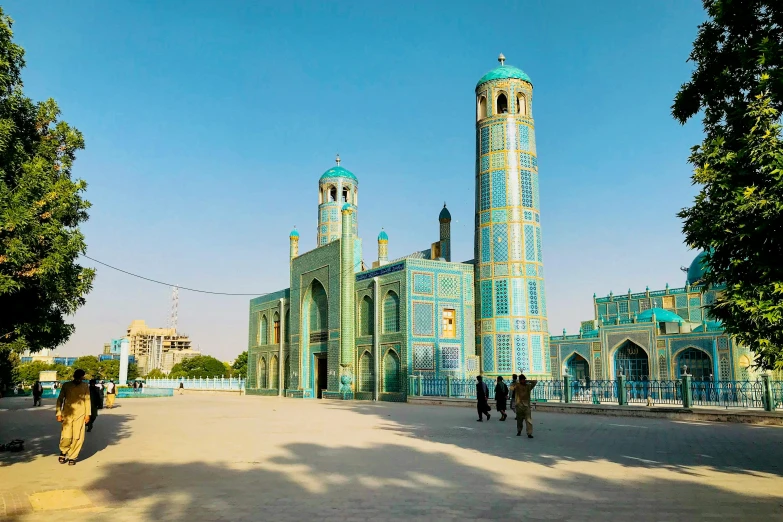 people walking by a large blue building with tall towers