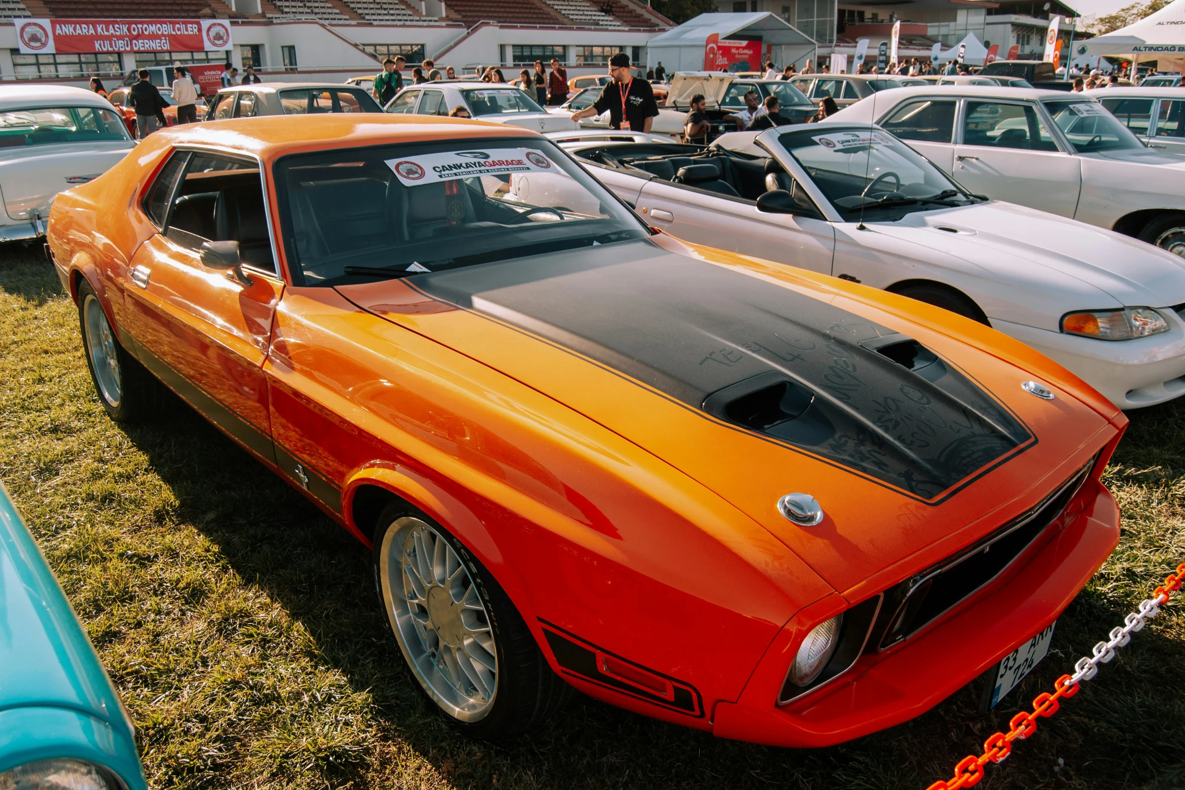 an orange mustang with black stripes parked at a show