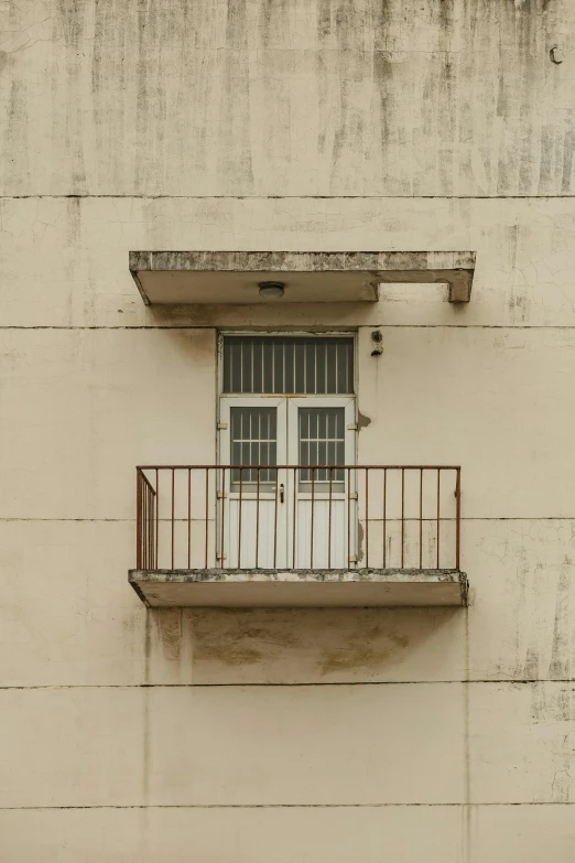 an old building with two windows and one metal balcony