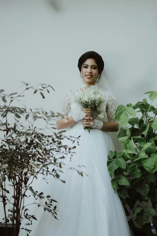 a woman in a dress stands with a bouquet of flowers