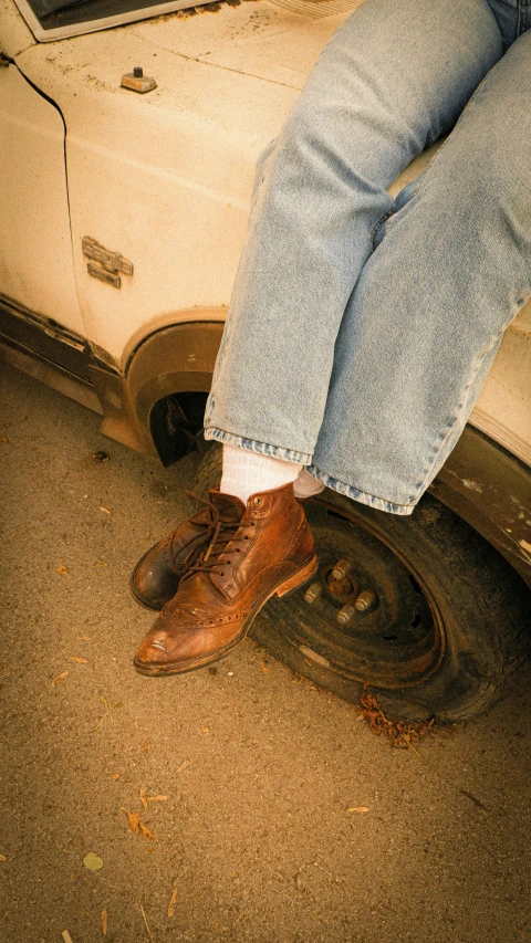 a person in blue jeans standing next to a car