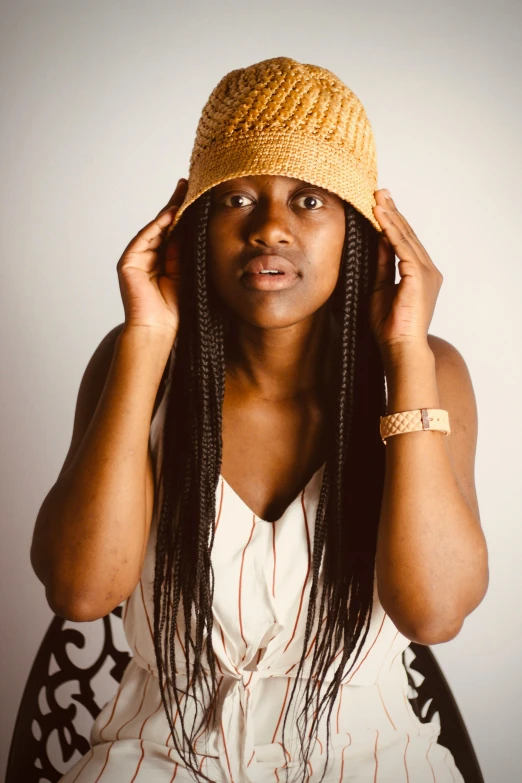 a woman with a crochet hat holds her hand up to her face