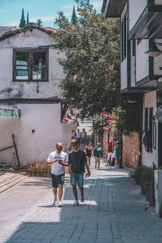 people walking in street next to white building with green trees