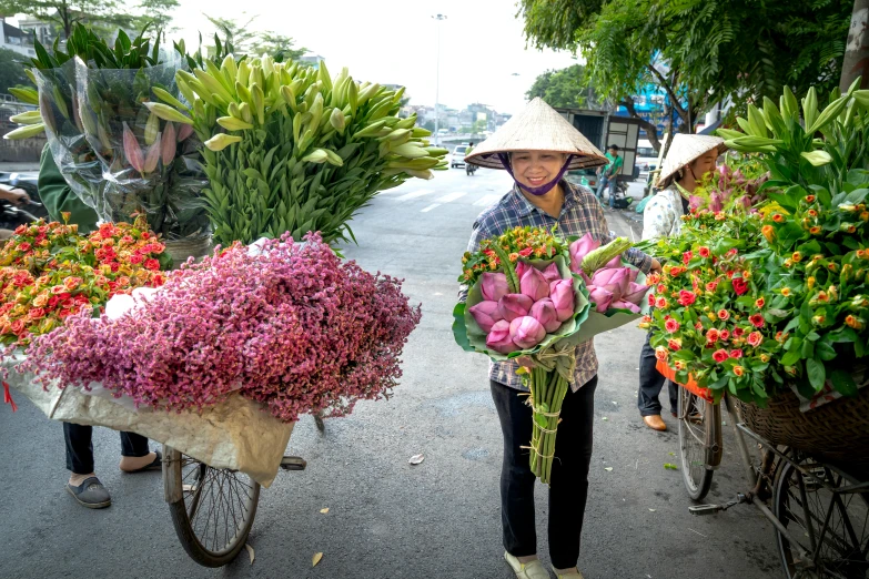 an asian woman with baskets of flowers walks down the street