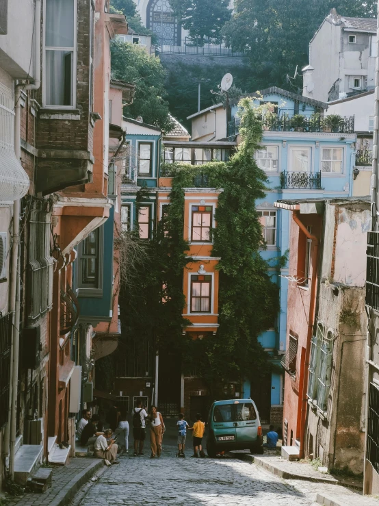 many people standing near buildings and a car on the street