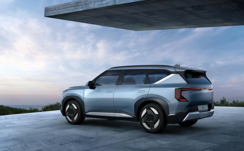 a sleek and futuristic blue electric vehicle is parked in front of a concrete cliff