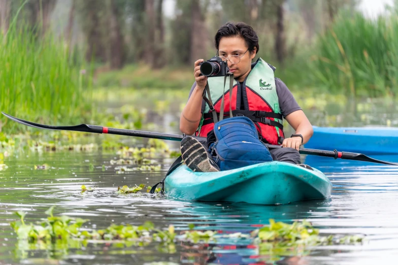 a person in a blue boat with a camera taking a po