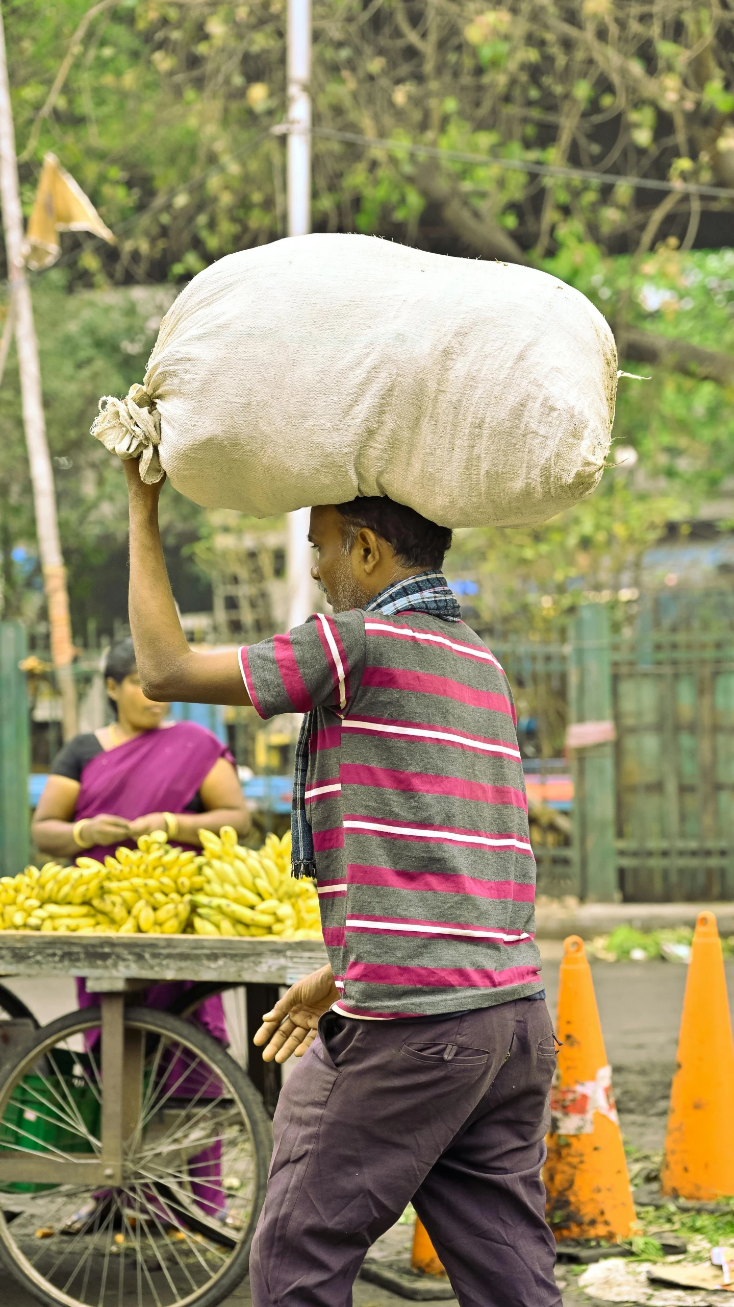 a child carries a big sack of groceries on his head