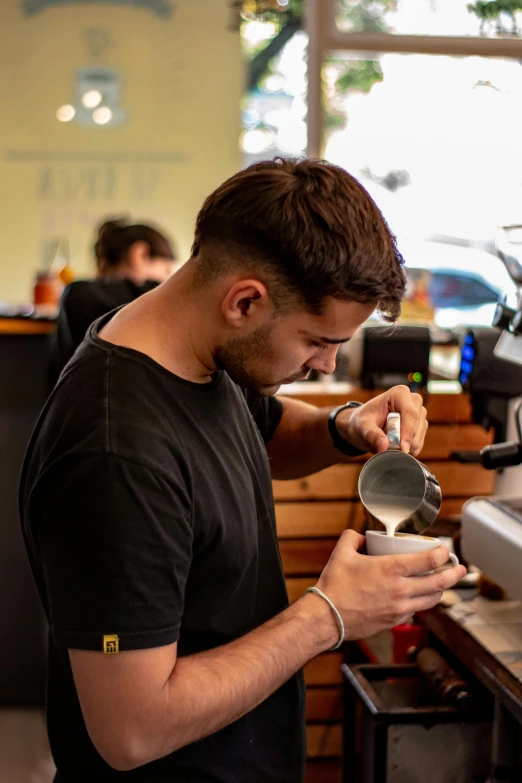 man looking down at his cell phone while using an espresso machine