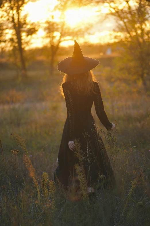 the witch in her dress in front of the setting sun