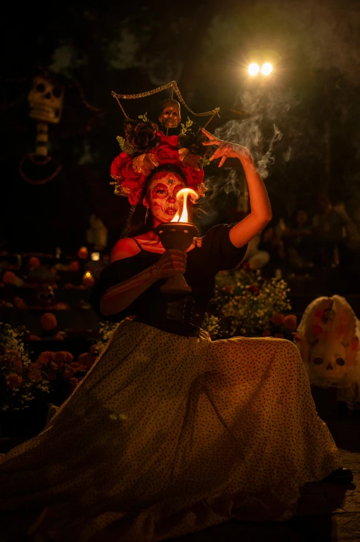 a woman in costume sitting outside near a fire and some people