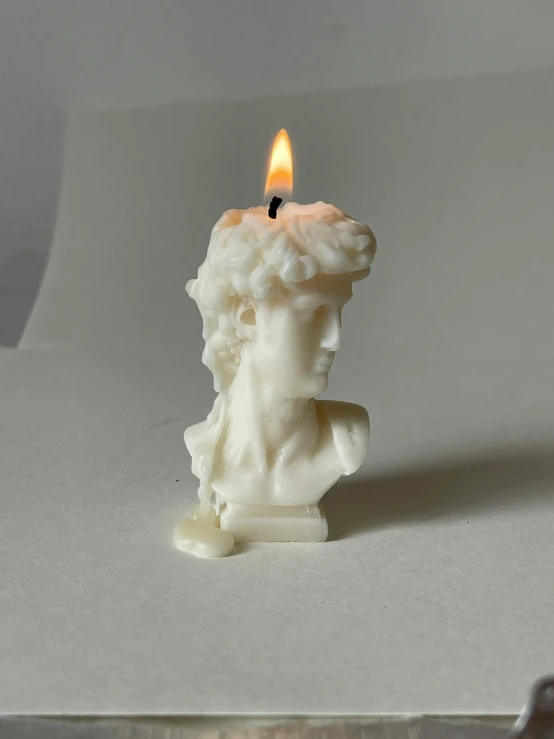 a candle with a small head that is lit