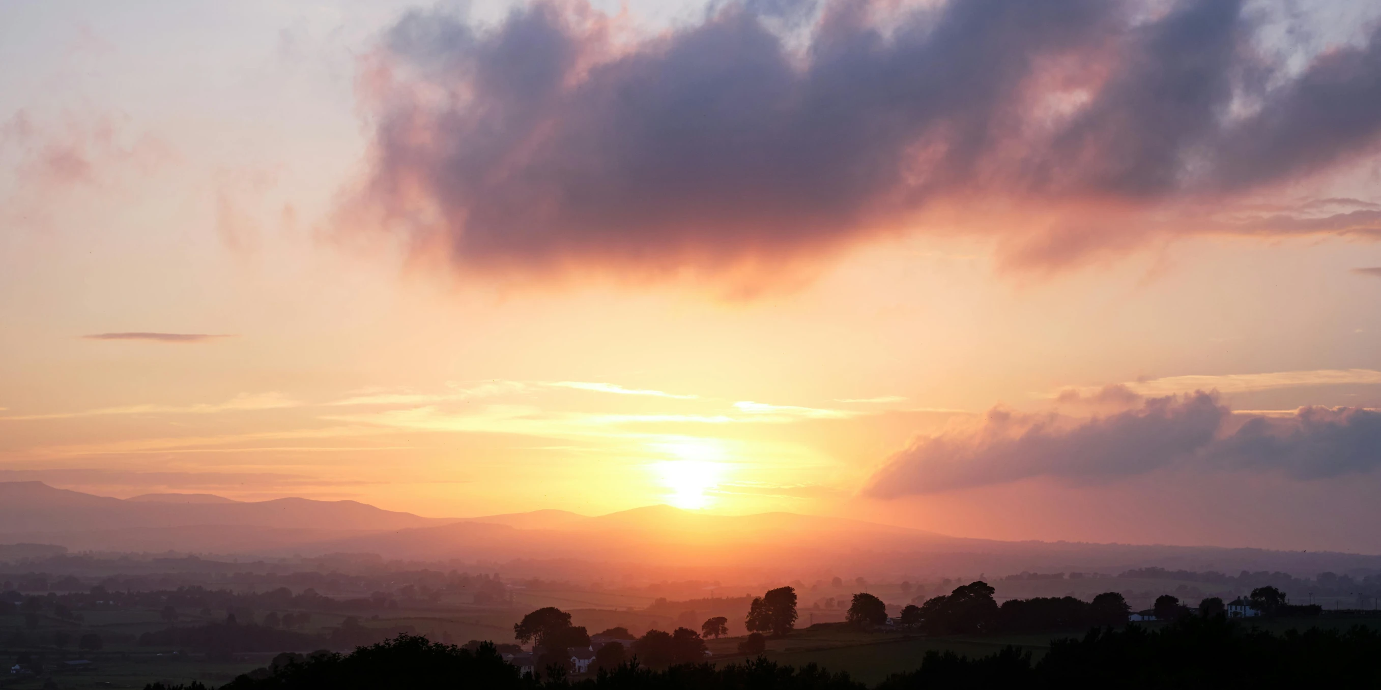 the sun rises over a valley as it reflects in the water