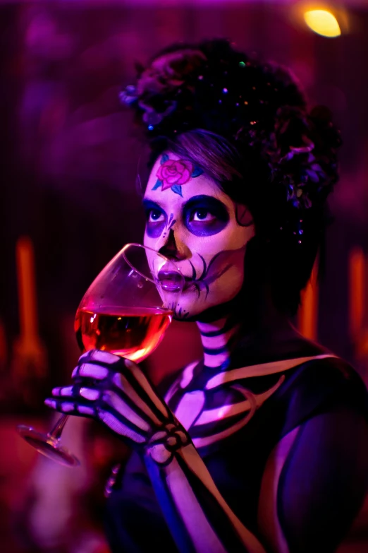 a woman in a skeleton makeup and body painting drinking a glass of wine