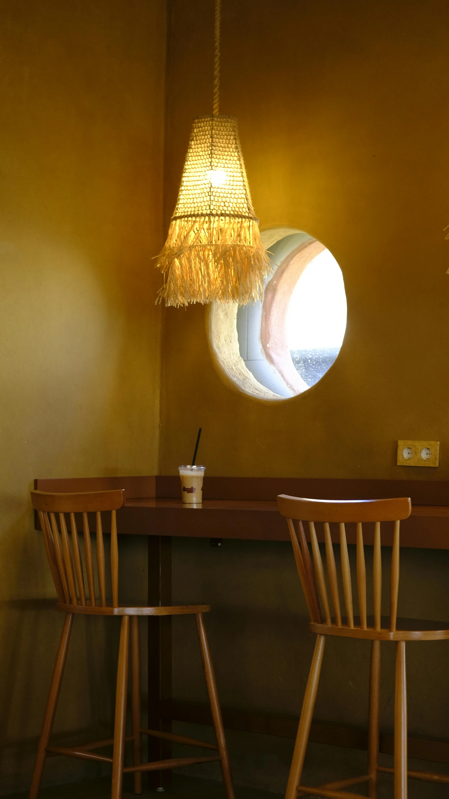 two wooden chairs sitting under a light hanging from a ceiling
