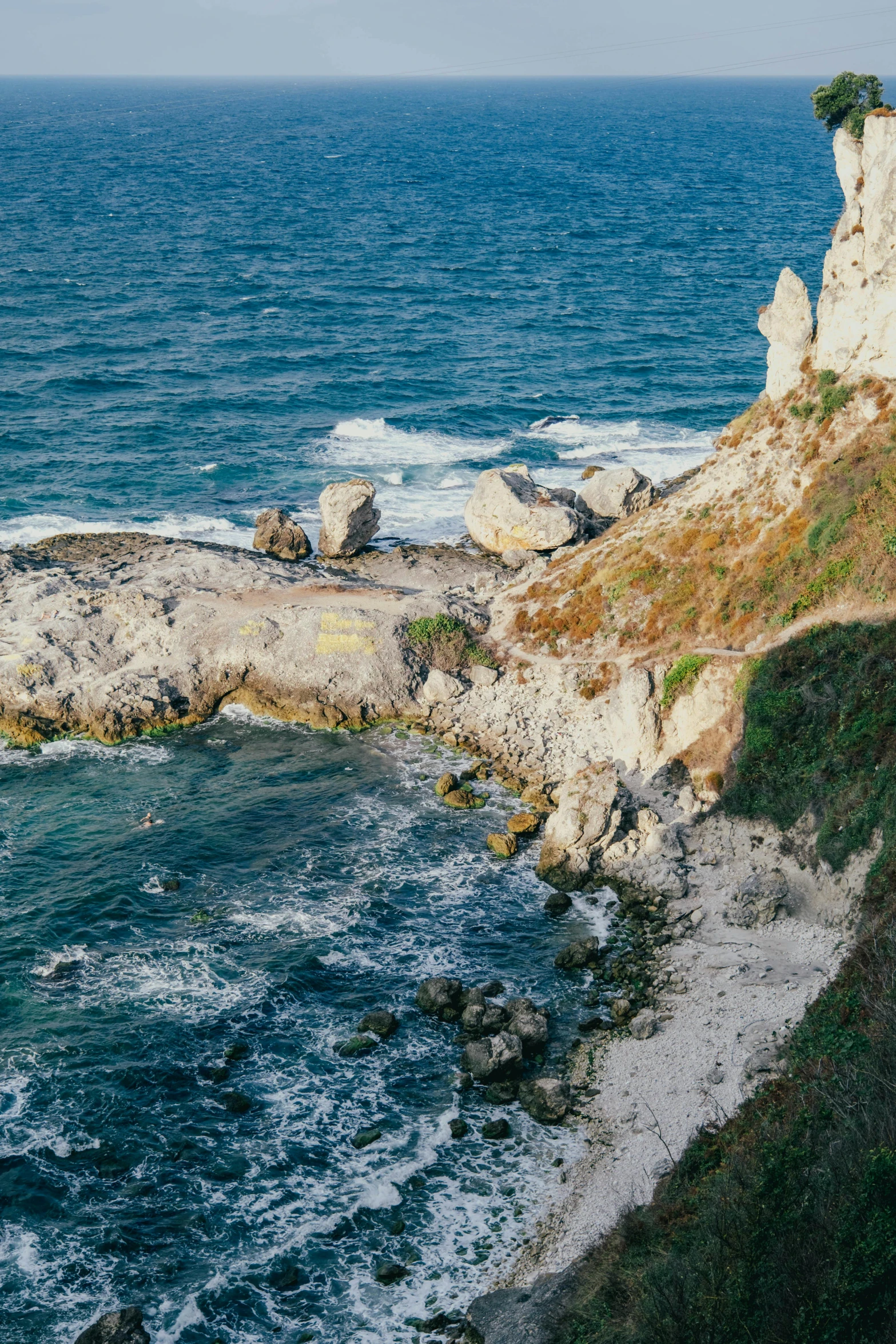 the ocean is blue with white waves near a cliff