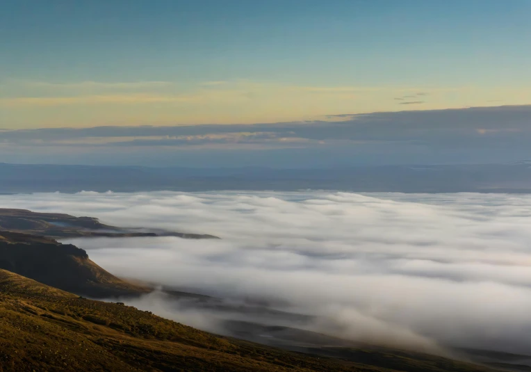 a hill covered in clouds, surrounded by hills