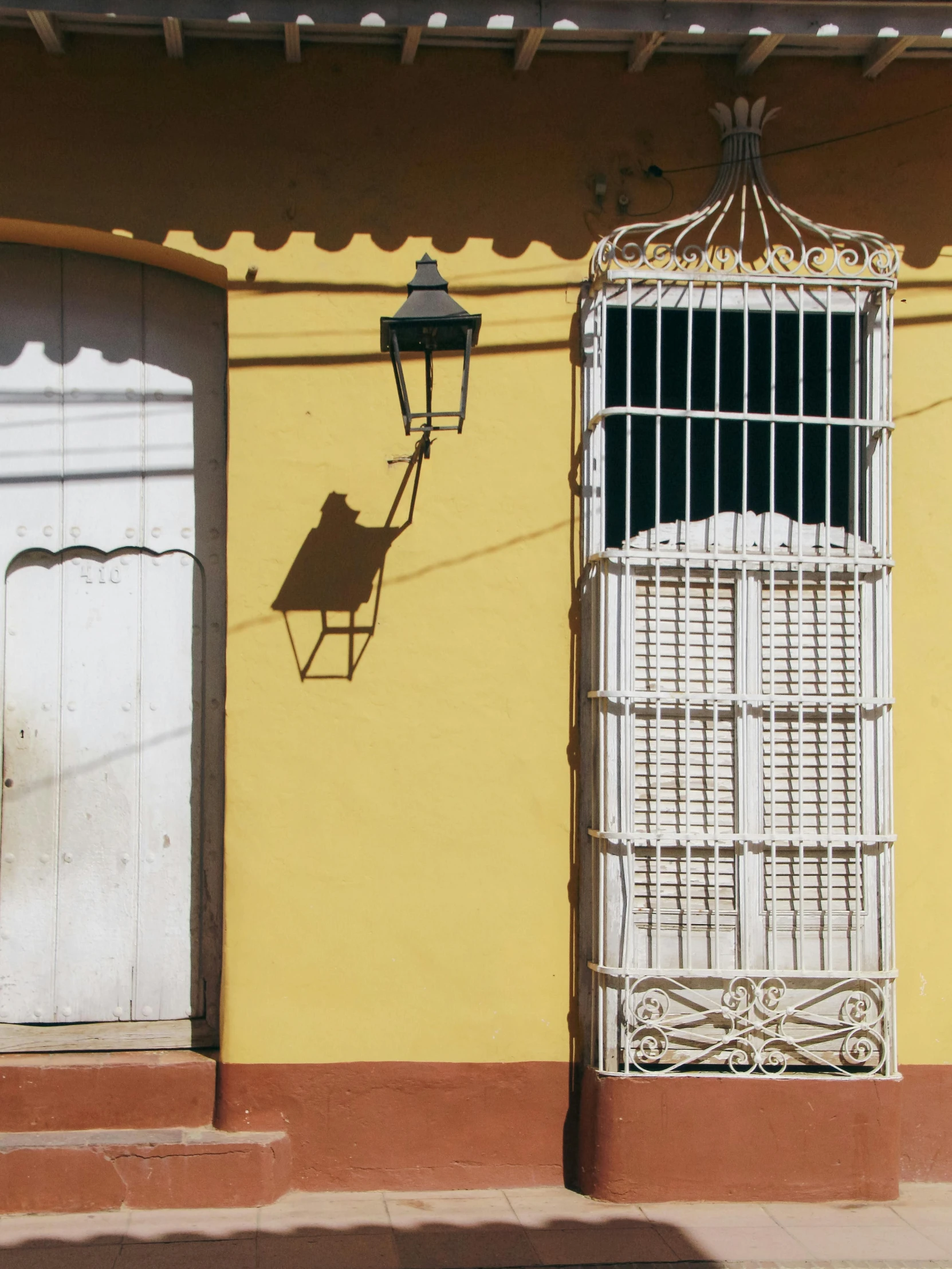 the street lamp is attached to a building in an area with yellow walls