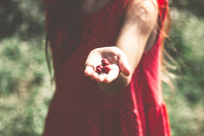 a girl is holding out her hand while holding some fruit