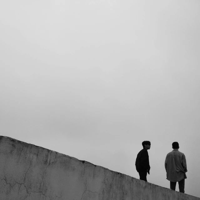 two men standing at the top of a cement wall