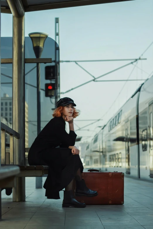 a woman is sitting on a bench at a train station